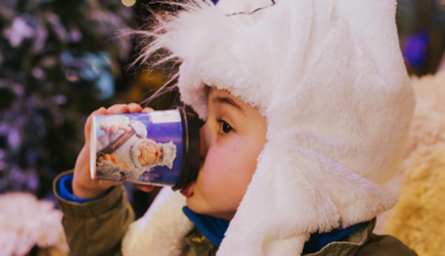 Criança bebendo café num copo temático snowland